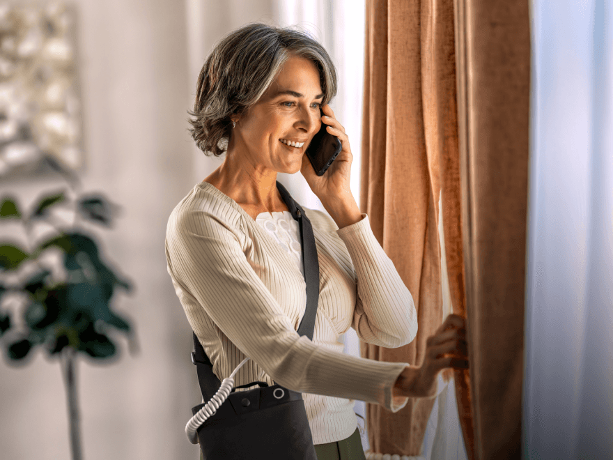 Patient wearing Optune Lua device on phone representing MyNovocure support service 