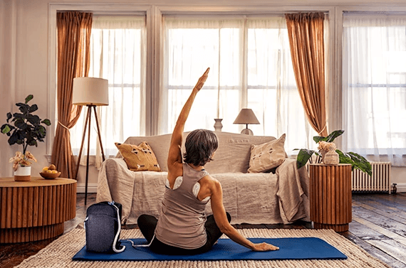 Woman practicing yoga in a bright, cozy living room with plants and natural light